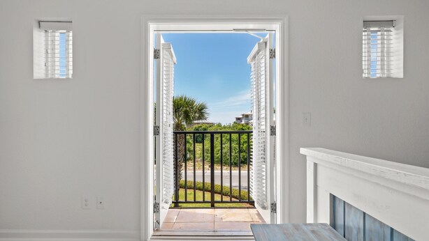 A doorway leading to a balcony with a view of a street and greenery. - Spacious 4BR • Pool • Arcade • Walk to Beach • BBQ (Panama City Beach)