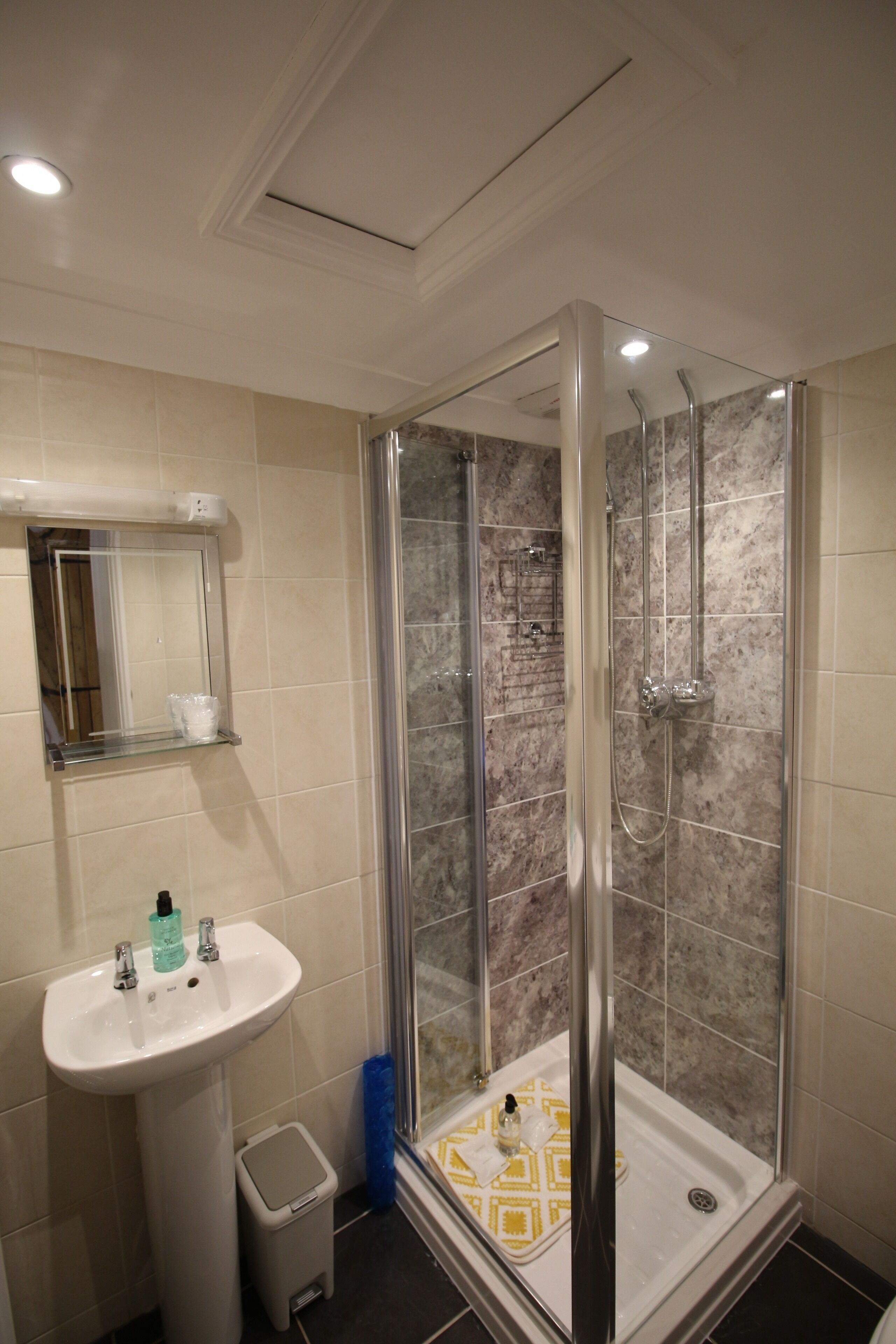 A bathroom with a glass-enclosed shower, a sink, and a mirror.