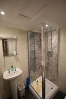 Un baño con ducha envuelta en vidrio, un lavabo y un espejo.