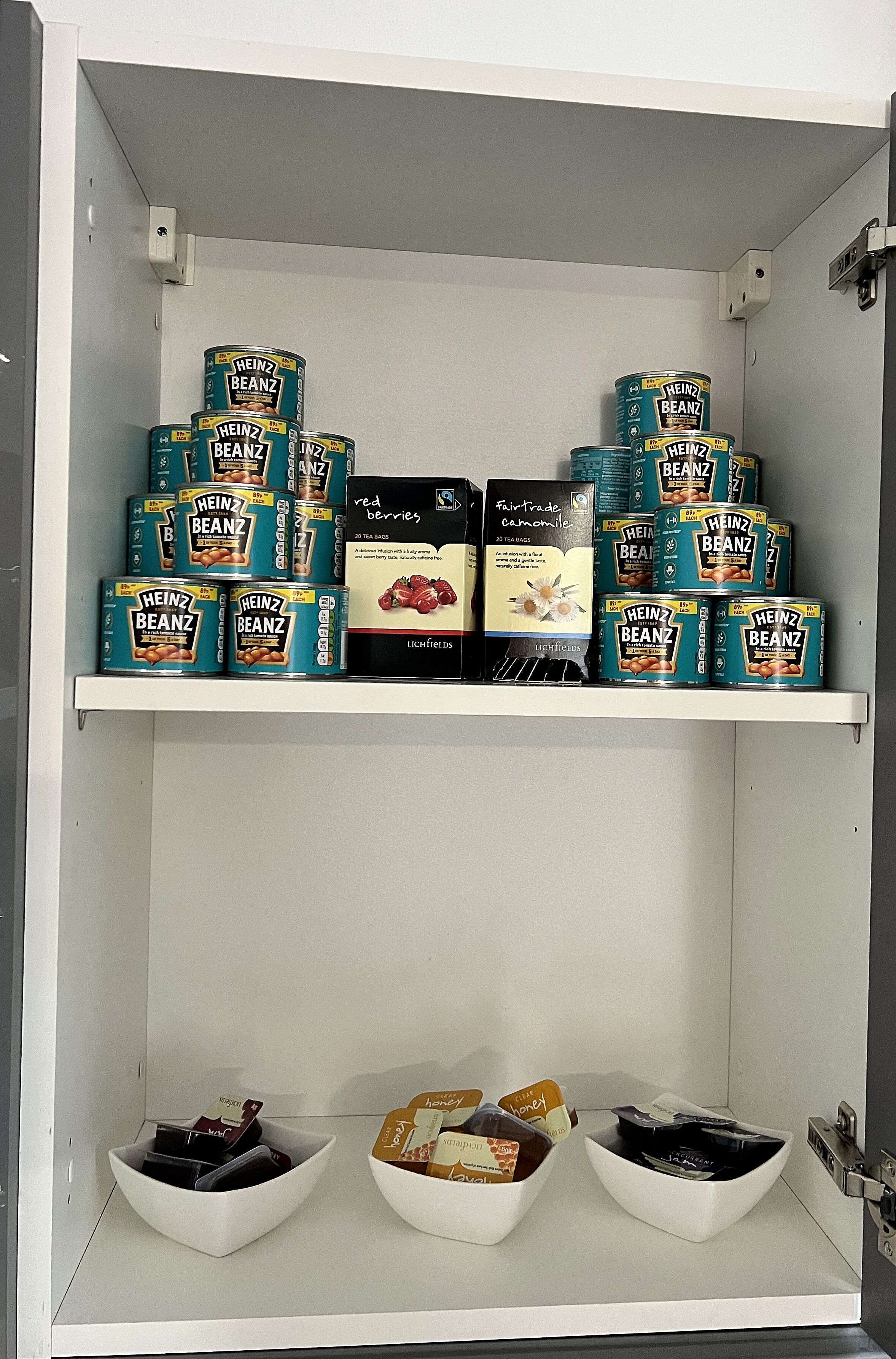 Una despensa con varias estantes repletos de Heinz Beanz, bayas rojas y otros alimentos.
