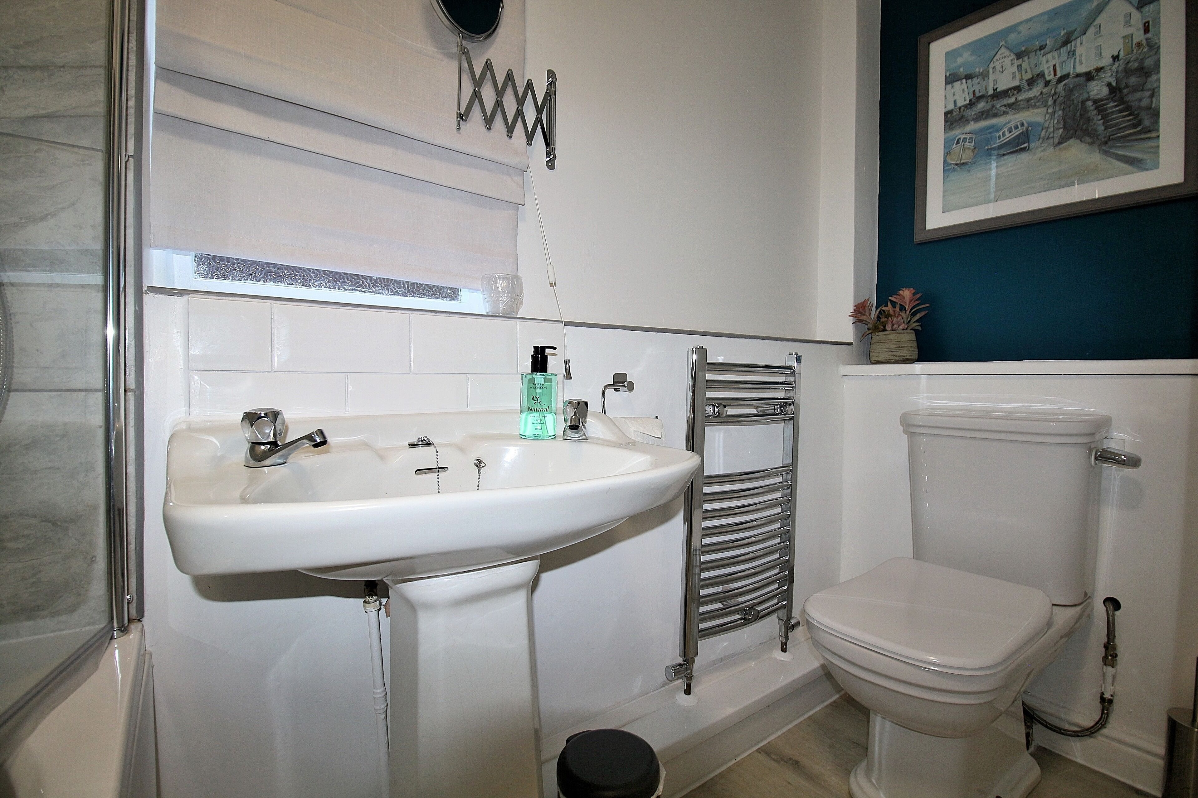 Un baño con lavamanos blanco, inodoro y toallero.