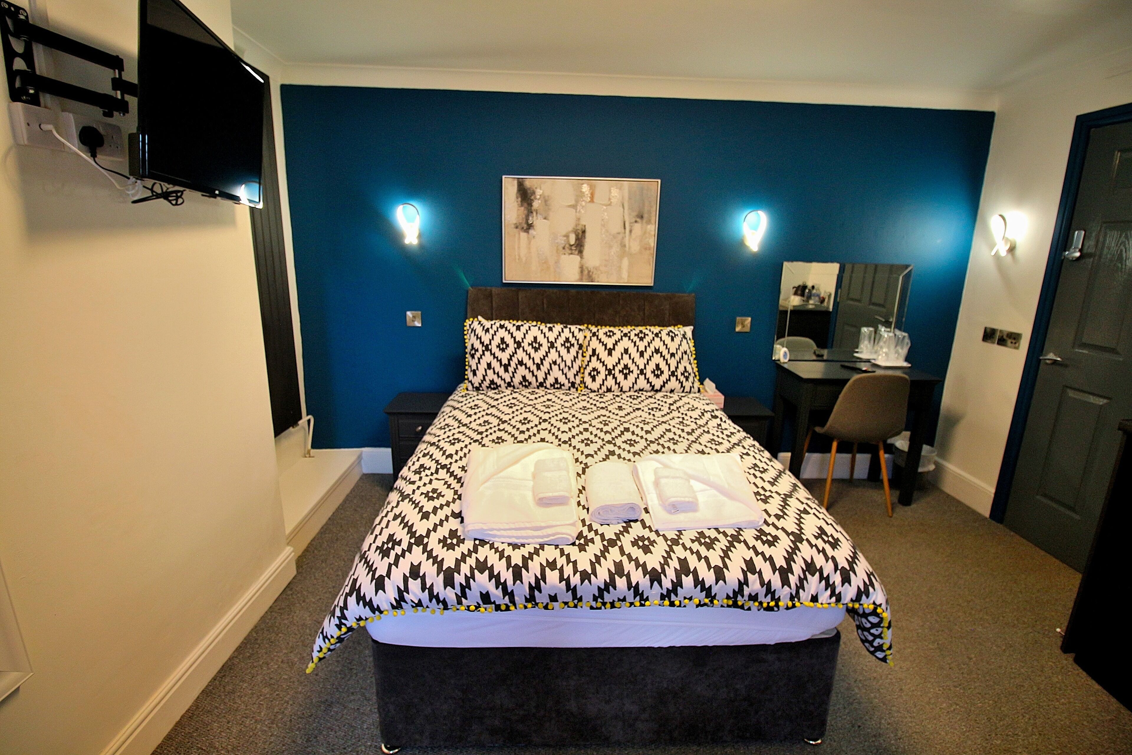 A hotel room with a bed, a desk, and a chair.