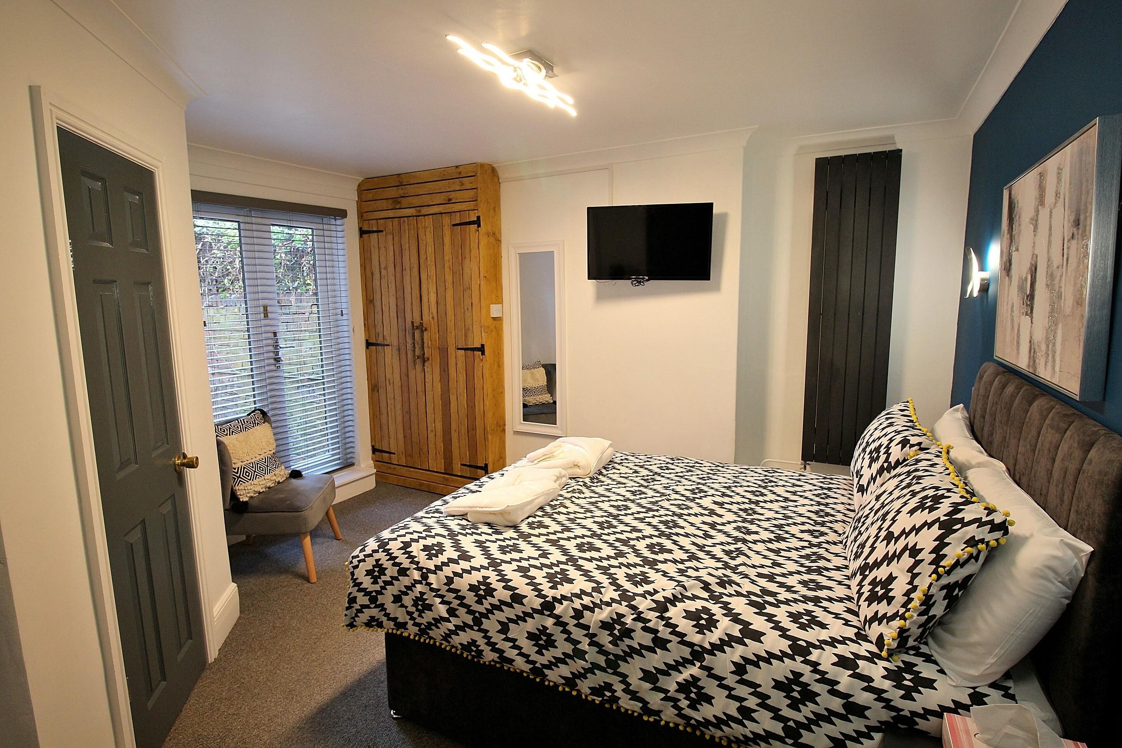A bedroom with a bed, a television, and a wooden wardrobe.