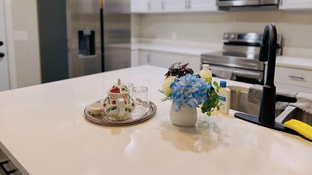 Een moderne keuken met witte kasten, roestvrijstalen apparatuur en een wit aanrecht.