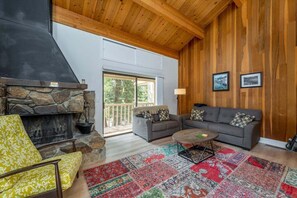 Cozy living room with a fireplace, sofa, and vibrant rug, featuring a large window and balcony access.