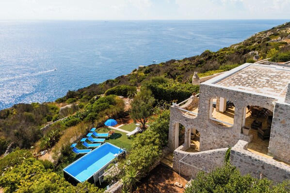 A coastal property with a swimming pool, lounge chairs, and a stone building with arches. - Villa Petra by BarbarHouse (Gagliano del Capo)