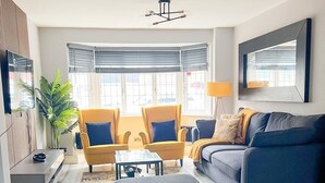 Una sala de estar moderna con un sofá, sillones, una mesa de centro y un televisor.
