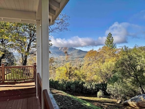 Una terraza de madera con vistas a un paisaje montañoso y follaje otoñal.