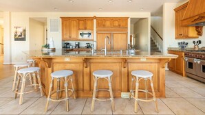 Una cocina amplia con una isla grande, armarios de madera y una campana extractora de acero inoxidable.
