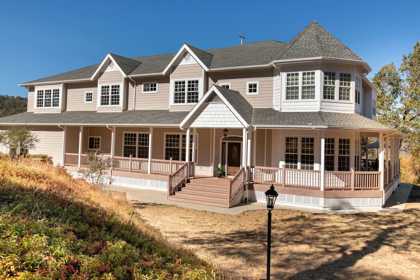 A large, two-story house with a wrap-around porch, multiple windows, and a steeply pitched roof.