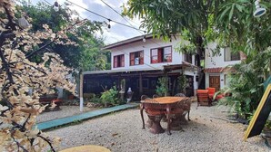 A house with a covered patio, outdoor seating, and a garden with various plants. - Cristina's (Cóbano)
