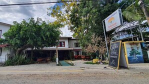 A building with a covered outdoor seating area, a signboard for a restaurant, and a mural on the wall. - Cristina's (Cóbano)