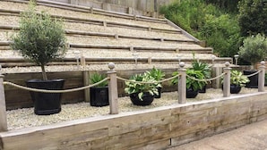 A tiered seating area with wooden railings and potted plants. - The Mumbles - Bungalow - 2 Bedrooms - Pet Friendly (Swansea)