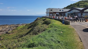 A coastal restaurant with outdoor seating overlooking the sea. - The Mumbles - Bungalow - 2 Bedrooms - Pet Friendly (Swansea)