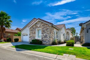A residential house with a stone facade, a garage, and a well-maintained lawn. - Painted Canyon, Joshua Tree, Coachella, and You (Indio)