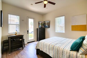 Un dormitorio con cama, escritorio, silla, ventilador de techo y ventana.