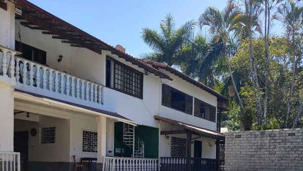 A two-story house with a swimming pool, a balcony, and a brick wall. - Space 579 is the ideal place for you and your family! (Miguel Pereira)