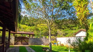 A stone pathway leading to a wooden gate, surrounded by lush greenery and a stone wall. - Space 579 is the ideal place for you and your family! (Miguel Pereira)