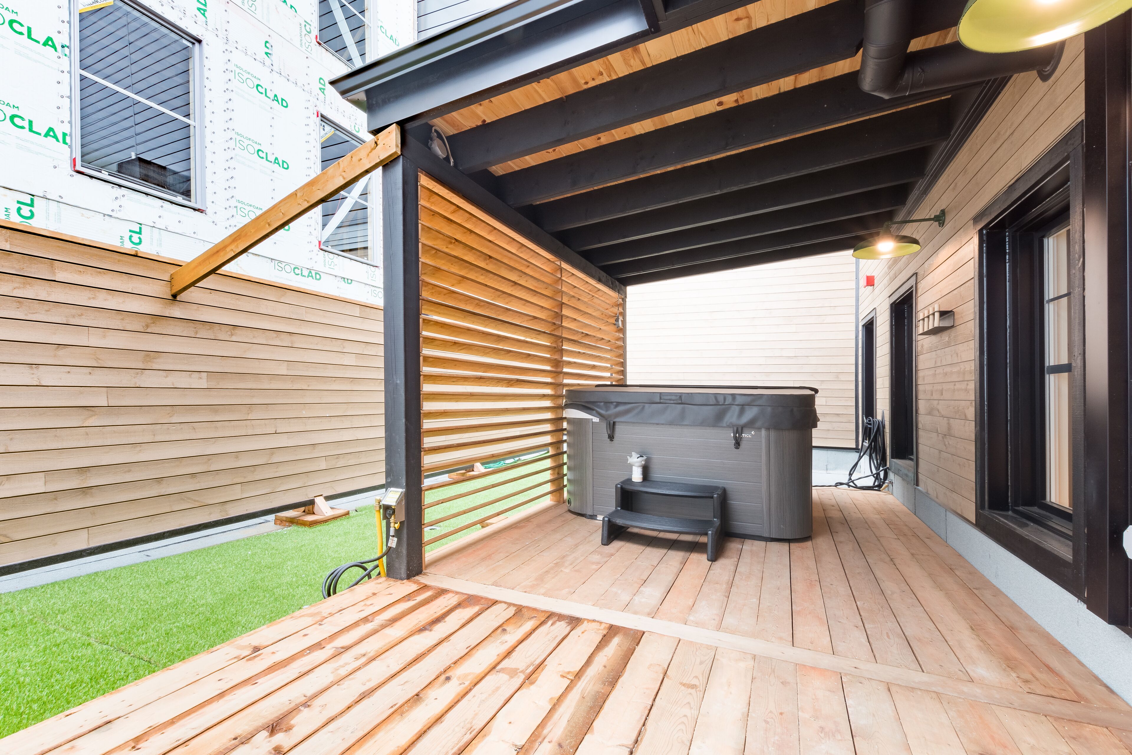 An outdoor wooden deck with a hot tub, a small table, and a bench.