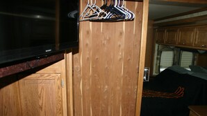 Een compact RV-interieur met houten inrichting, een flatscreen-tv en een klein zitgedeelte.
