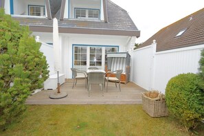 A house with a covered patio, a white fence, and a small garden. - Haus Sommer am Munkmarscher Strand (Munkmarsch)