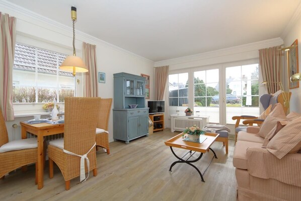 A cozy living room with a dining area, a blue cabinet, a sofa, and a table with a vase. - Haus Sommer am Munkmarscher Strand (Munkmarsch)