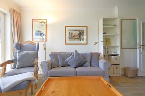 Ein Wohnzimmer mit einer Couch, einem Sessel und einem Holztisch.