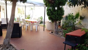 An outdoor patio area with a table and chairs, surrounded by potted plants and a tree. - Beach house 9 places independent with garden and barbecue CIN IT081020C23DP4ZB5R (San Vito Lo Capo)