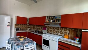 A compact kitchen with a refrigerator, microwave, stove, and red cabinets. - Beach house 9 places independent with garden and barbecue CIN IT081020C23DP4ZB5R (San Vito Lo Capo)