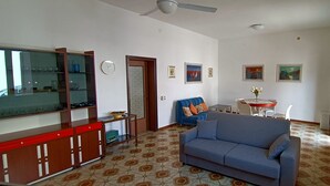 A living room with a sofa, a television, a dining table with chairs, and a cabinet. - Beach house 9 places independent with garden and barbecue CIN IT081020C23DP4ZB5R (San Vito Lo Capo)