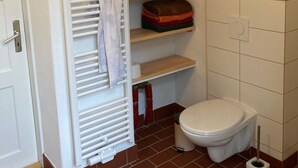 A bathroom with a white toilet, a towel rack, and shelves with folded towels and toiletries. - No letting via FEWO (Lärz)