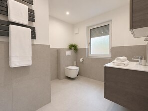 A modern bathroom with a toilet, sink, and towel rack. - Haus Waldluft, Whg. Buche, Am Großen Brink 13, 27476 Cuxhaven- Sahlenburg (Cuxhaven-Sahlenburg)