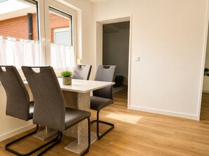 A dining area with a table, four chairs, and a potted plant. - Haus Waldluft, Whg. Buche, Am Großen Brink 13, 27476 Cuxhaven- Sahlenburg (Cuxhaven-Sahlenburg)