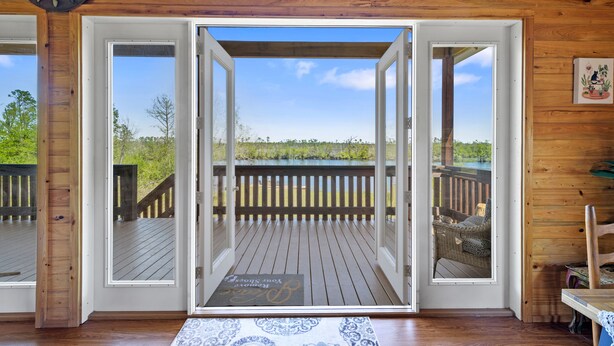 A wooden interior with a view of a wooden deck and a body of water. - Beautiful log cabin w/ private dock, gameroom, 23mi to beach, 3bd2ba, sleeps 11 (Youngstown)
