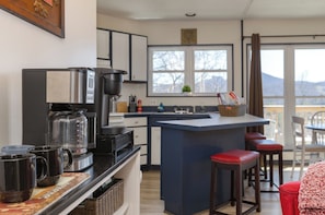 Una cocina moderna con cafetera, un ventanal grande y una barra con taburetes.