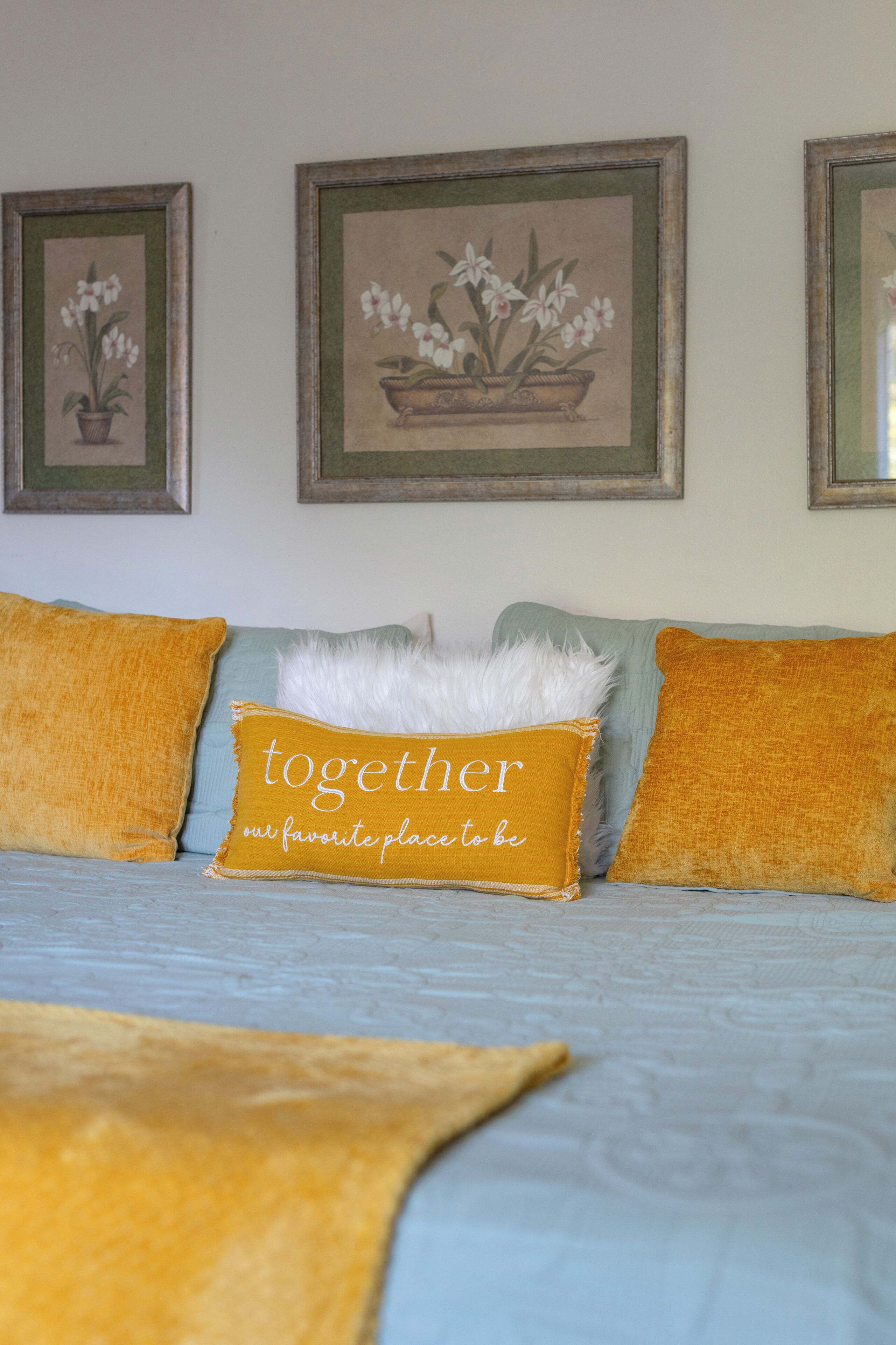 Ein Bett mit blauer Bettdecke, zwei Kissen und einem dekorativen Kissen mit Text.