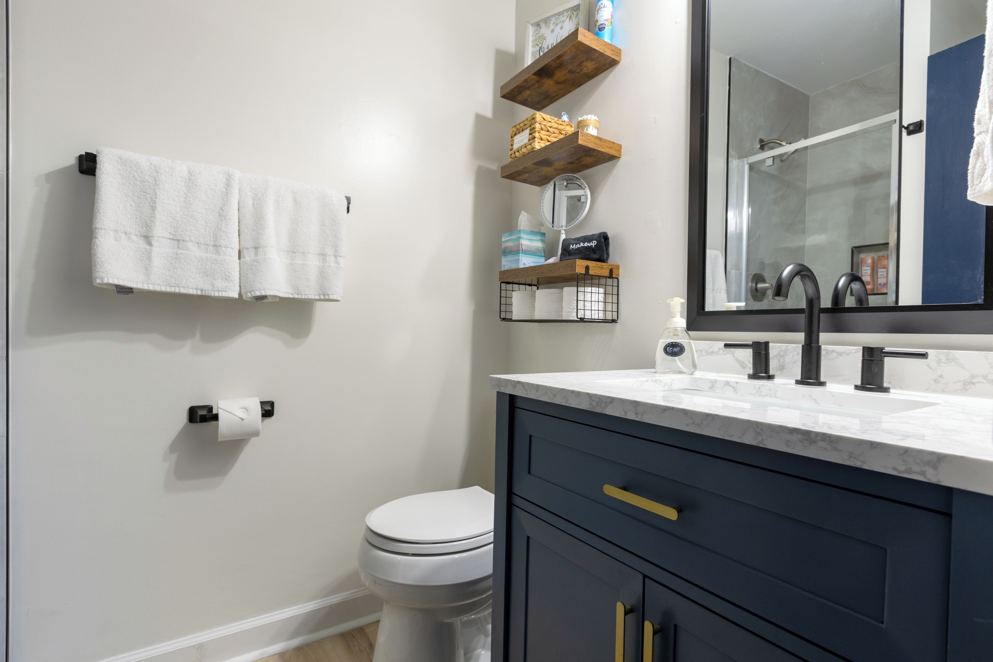 Une salle de bain comprenant des toilettes, un lavabo avec un miroir et un porte-serviettes.