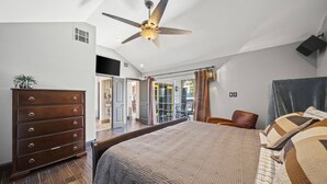 Un dormitorio con una cama grande, un ventilador de techo, un aparador y vistas al exterior.