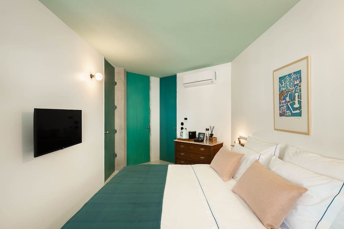 Un dormitorio con cama, cómoda, televisor y puerta.