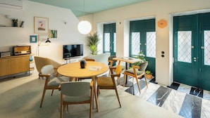 Una sala moderna con una mesa redonda de madera, sillas cómodas, un televisor de pantalla plana y un ventanal con vistas al exterior.