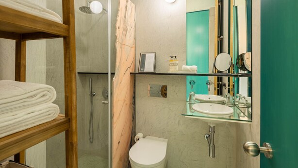 Ein modernes Badezimmer mit Duschkabine aus Glas, Toilette, Waschbecken mit Glastablarett und Spiegel mit Holzrahmen.