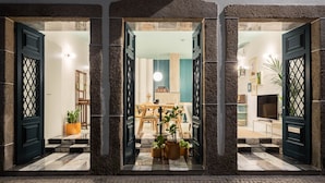 Entrada de hotel con diseño moderno, que presenta un amplio acceso central flanqueado por dos puertas grandes.