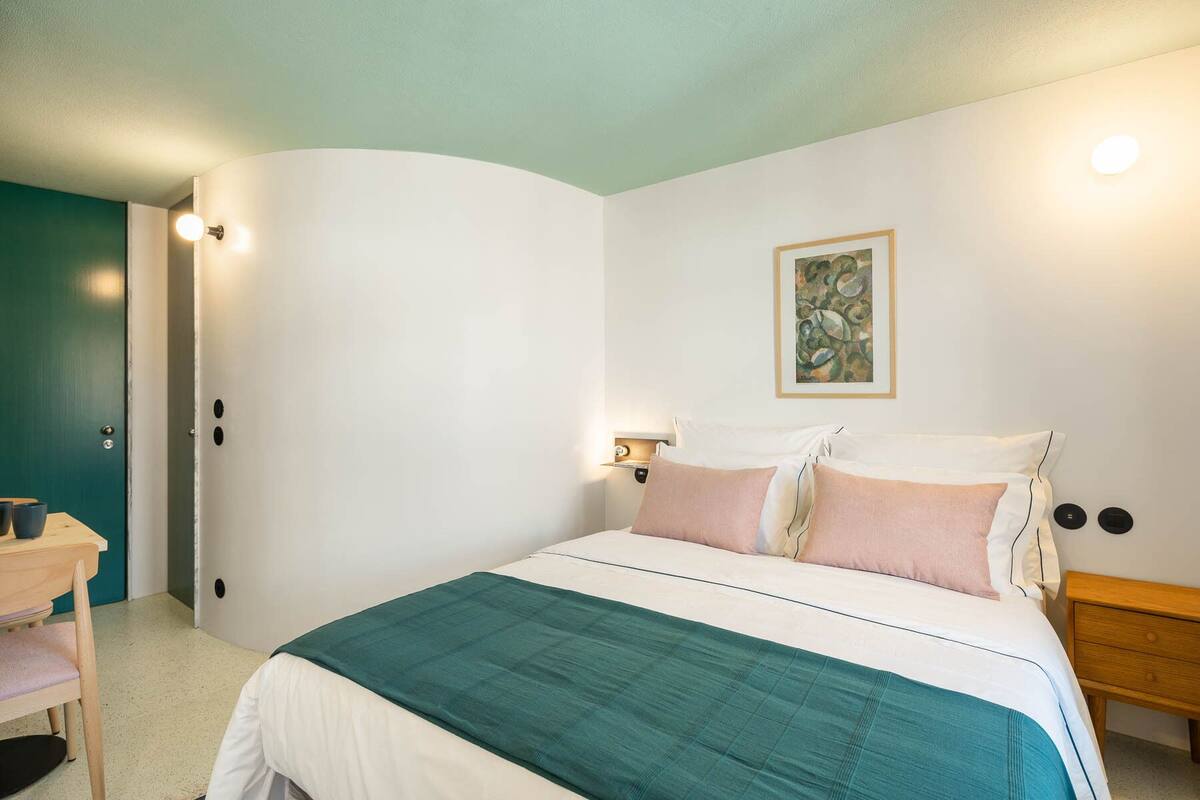 Un dormitorio con una cama, una mesita de noche y un cuadro en la pared.