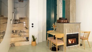 Una sala de estar moderna con chimenea, una mesa de comedor con sillas y una escalera con escalones de mármol.