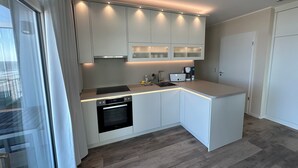 A modern kitchen with white cabinetry, a built-in oven, and a coffee maker. - Anna Düne 3-44 - Exclusive sea view at Aparthotel Anna Düne (Wangerooge)