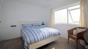 A bedroom with a bed, a chair, a window, and a lamp. - Stones throw from the sea (Seaford)