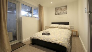 Un dormitorio con una cama, una ventana, un radiador y una mesita.