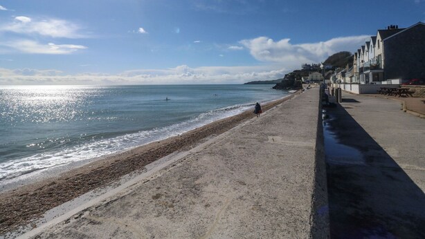 A beach with a concrete walkway, a row of seaside houses, and the ocean. - Wrens Nest (Kingsbridge)