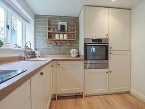 A kitchen with a built-in oven, a coffee machine, and a shelf with jars. - Wrens Nest (Kingsbridge)