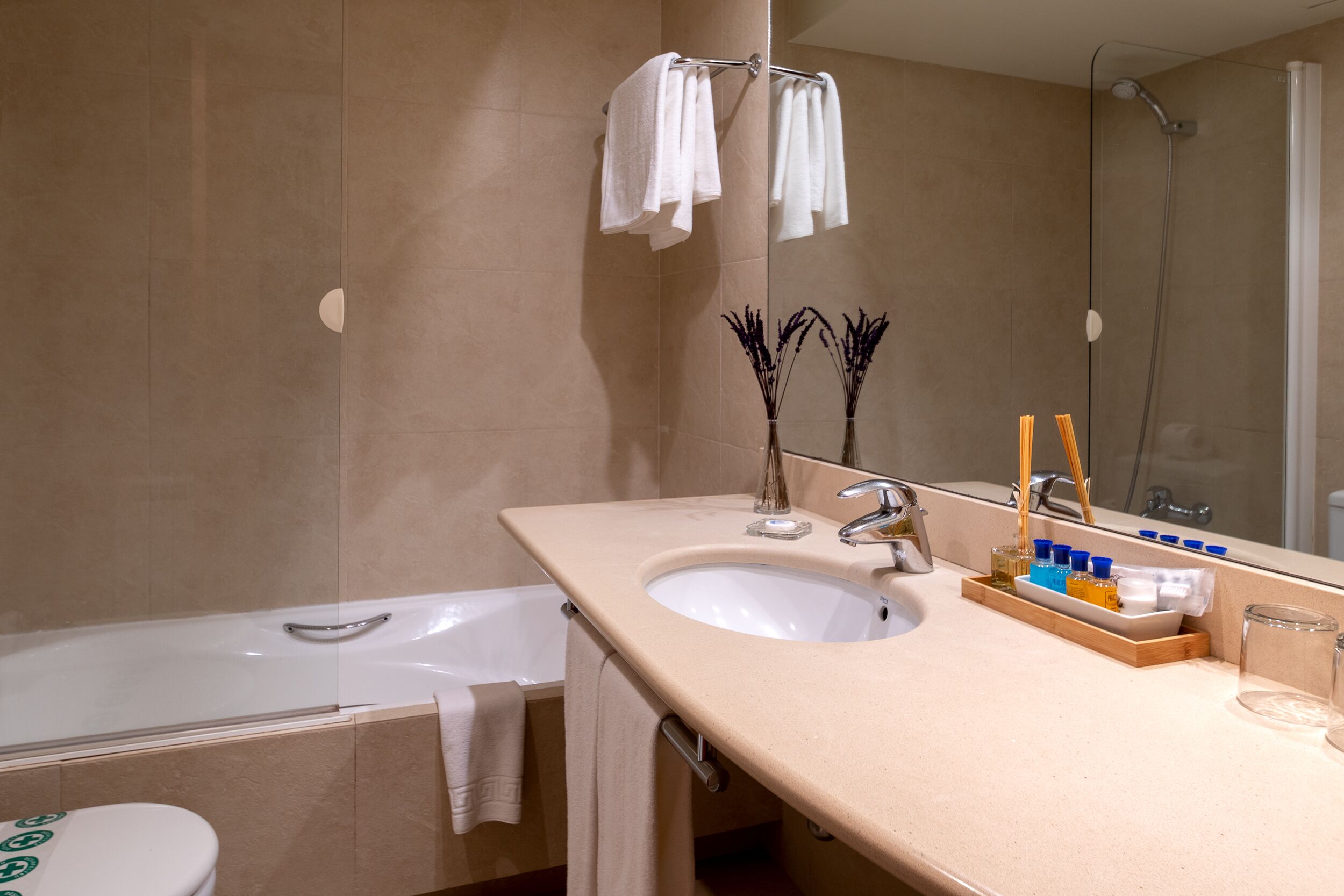 A bathroom with a bathtub, a sink, a mirror, and toiletries.